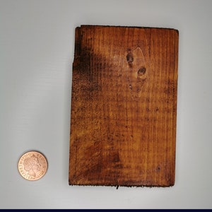 May include: A close-up of a rectangular piece of wood stained a dark brown color. The wood has a natural grain pattern and a few knots. The wood measures approximately 9.5 inches by 14.5 inches.