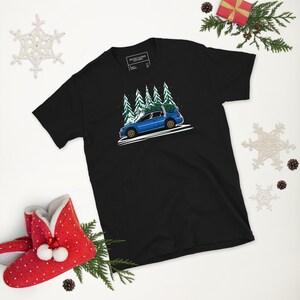 May include: A black t-shirt with a blue car carrying a Christmas tree in a snowy forest scene. The text "FIRST ALLEY GARAGE" is printed on the tag.