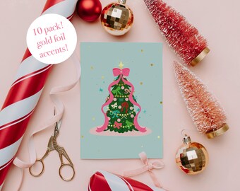 May include: A festive Christmas card featuring a decorated tree with pink ribbon and gold foil accents. The card is set against a light blue backdrop, with seasonal decorations like baubles and candy canes.