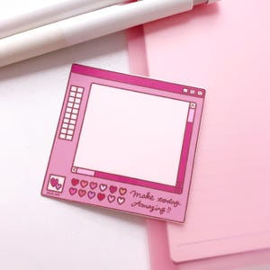 May include: A pink, computer-themed sticker with a blank screen, hearts, and the text "Make today Amazing!!". The sticker has a retro aesthetic and is on a pink background with pens.