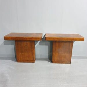 May include: Two wooden end tables with a rectangular top and a square base. The tables are made of dark wood with a natural finish.