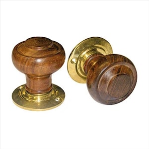 May include: Two wooden door knobs with brass trim. The knobs are round and have a raised centre. The brass trim is shiny and has a smooth finish.