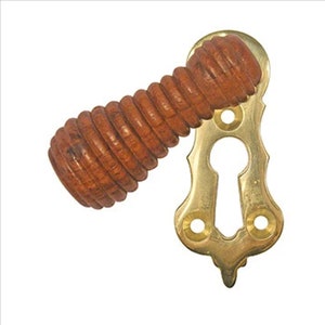 May include: A brass keyhole cover with an ornate design and a wooden knob. The knob is brown and has a spiral pattern.
