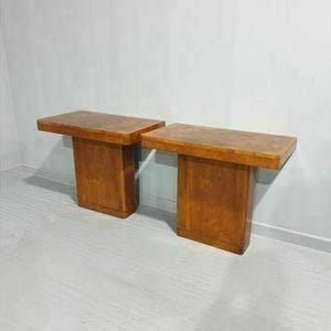 May include: Two wooden side tables with a light brown wood grain finish. The tables have a rectangular top and a square base.