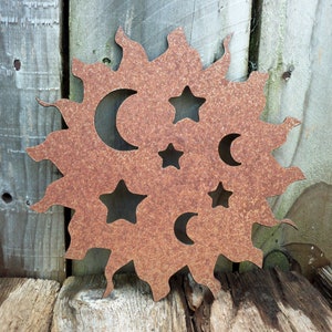 May include: A rusty metal sun with cut-out moons and stars. The sun is a decorative piece with a rustic look.