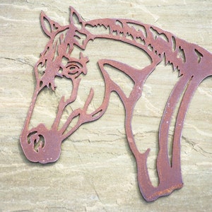 Puede incluir: Una silueta de cabeza de caballo de metal oxidado, una pieza de arte de pared decorativa.