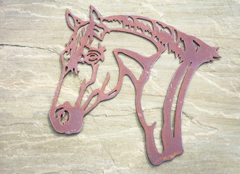 Puede incluir: Una silueta de cabeza de caballo de metal oxidado, una pieza de arte de pared decorativa.