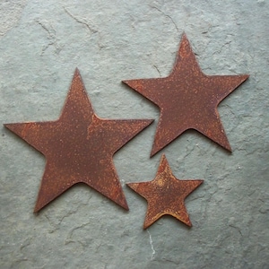 May include: Three rustic metal stars of different sizes, all with a rusty brown finish. The stars are arranged in a staggered pattern on a grey background.