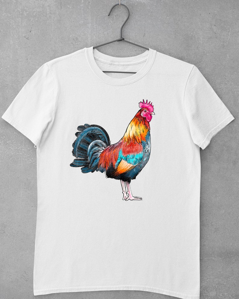 May include: White t-shirt with a colorful rooster illustration. The rooster is facing right and has a red, orange, yellow, blue, and black color scheme.