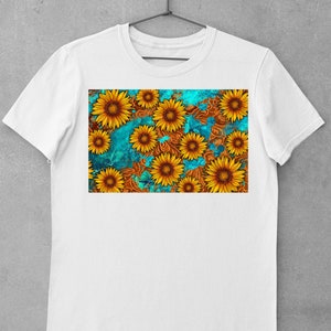 May include: White t-shirt featuring a vibrant sunflower design. The graphic showcases yellow sunflowers with brown centers against a teal and brown patterned background. The shirt is displayed on a hanger.