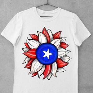 May include: White t-shirt with a red, white, and blue sunflower design. The center of the sunflower is a blue circle with a white star.
