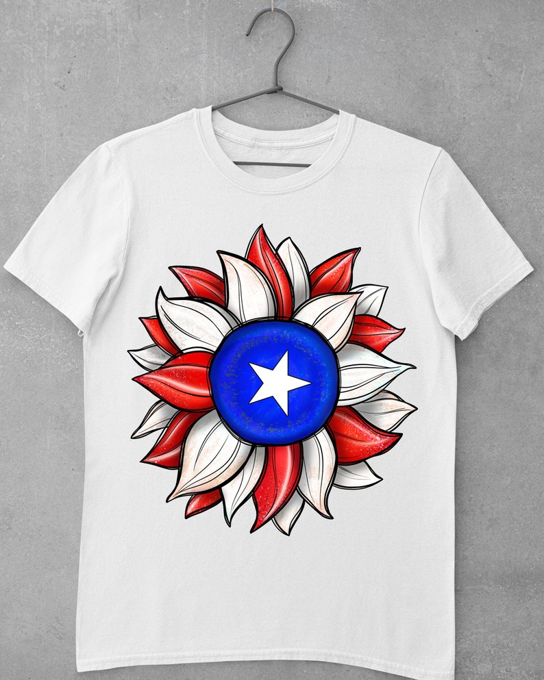 May include: White t-shirt with a red, white, and blue sunflower design. The center of the sunflower is a blue circle with a white star.