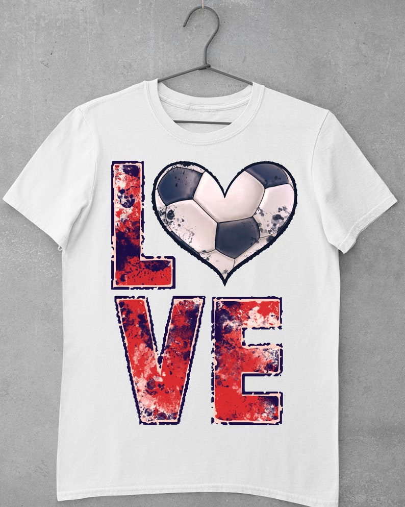 Puede incluir: Camiseta blanca con un gr&aacute;fico "LOVE" desgastado en rojo, blanco y azul. La "O" se reemplaza con un bal&oacute;n de f&uacute;tbol en forma de coraz&oacute;n.