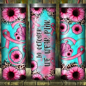 May include: Three stainless steel tumblers with a pink and teal design. The tumblers feature pink ribbons, sunflowers, and a pumpkin with a pink ribbon. The middle tumbler has the text "In October We Wear Pink".