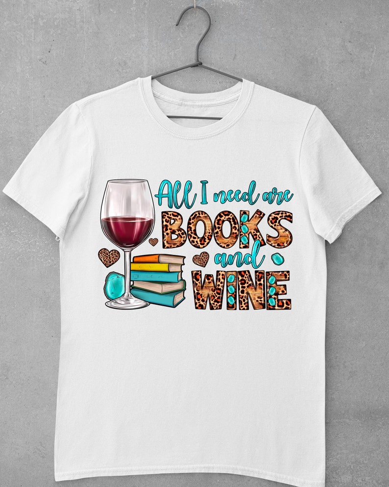 May include: White t-shirt with a graphic design of a glass of red wine, a stack of books, and the text "All I need are BOOKS and WINE".