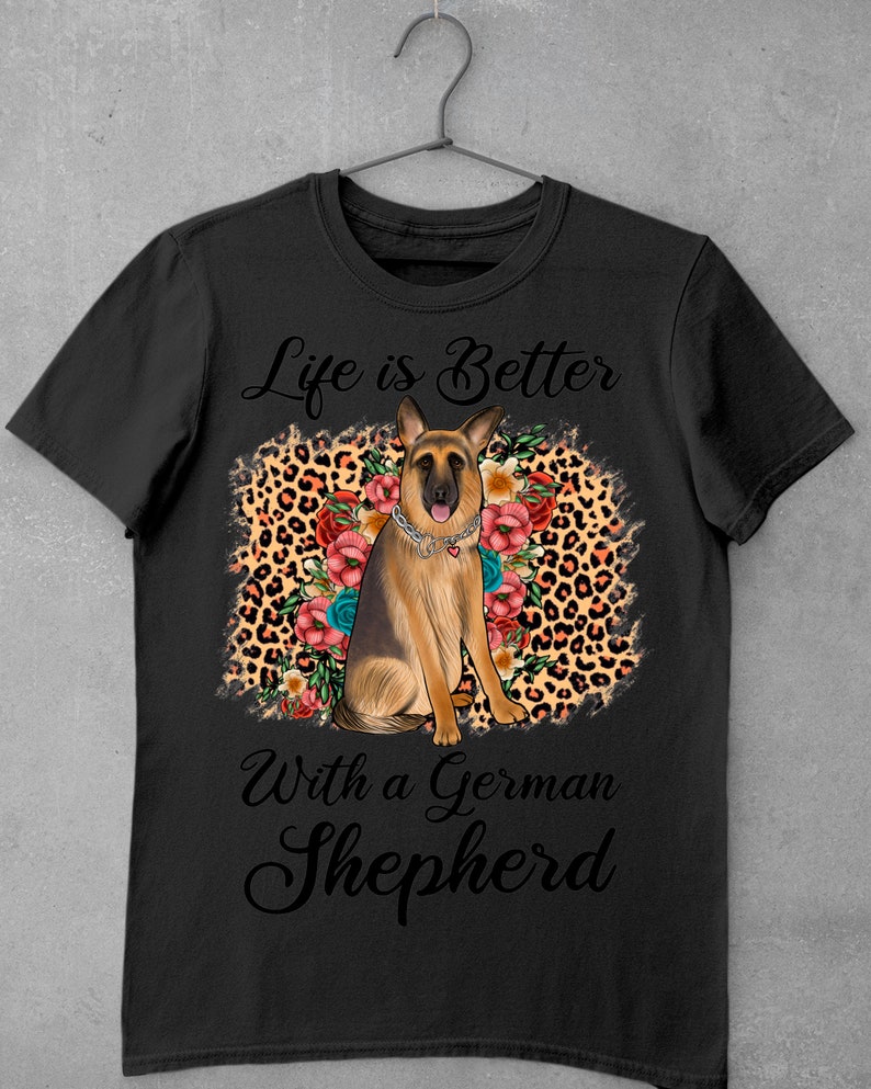 May include: Black t-shirt with a German Shepherd dog sitting on a leopard print background with flowers. The text "Life is Better With a German Shepherd" is printed on the shirt.