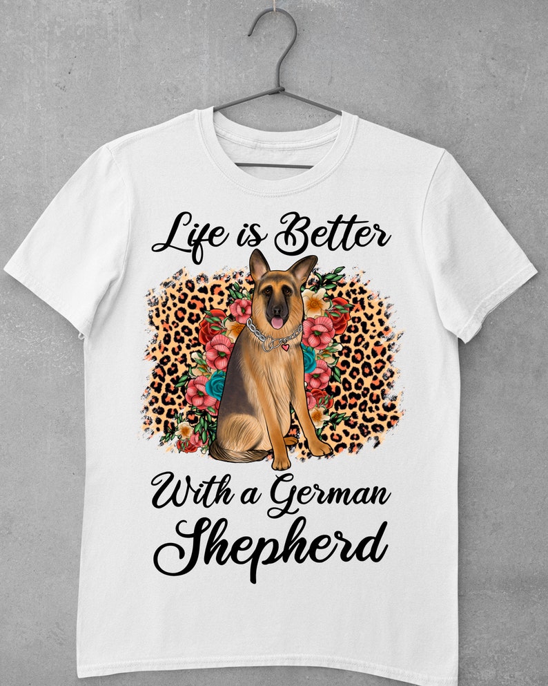 May include: White t-shirt with a German Shepherd dog sitting in a leopard print and floral design. The text "Life is Better with a German Shepherd" is printed on the shirt.