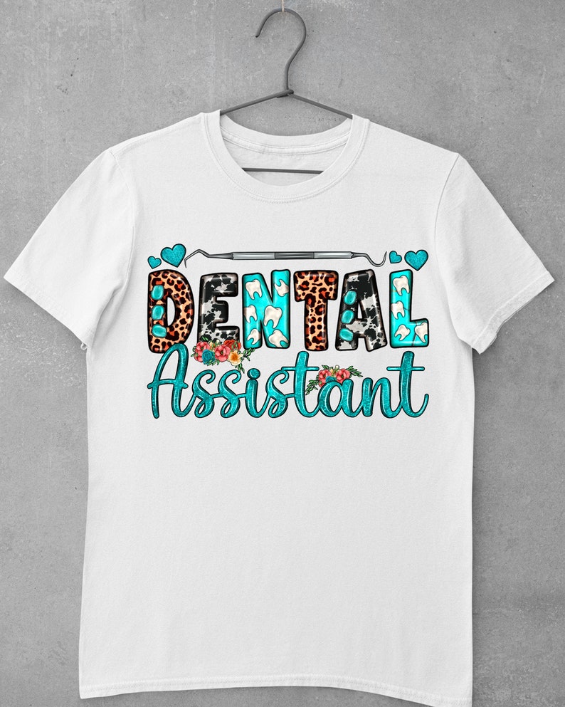 Op de afbeelding: Wit T-shirt met een turquoise ontwerp met de tekst "Dental Assistant". Het ontwerp bevat een tandheelkundig instrument, harten en dierenprintpatronen.