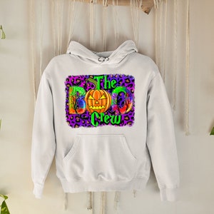 May include: White hooded sweatshirt with a graphic print of a pumpkin and the text "The Boo Crew" on a purple and leopard print background.