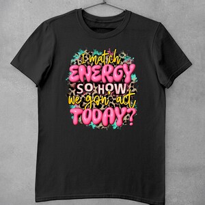 May include: Black t-shirt with a pink graphic that says "I match energy so how we gon' act today?" The graphic is surrounded by a leopard print pattern and blue paint splatters.