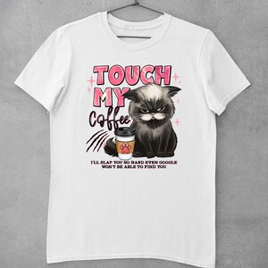 May include: White t-shirt with a black cat graphic holding a coffee cup. The text "TOUCH MY COFFEE" is in pink letters above the cat. Below the cat, the text reads "I'LL SLAP YOU SO HARD EVEN GOOGLE WON'T BE ABLE TO FIND YOU."