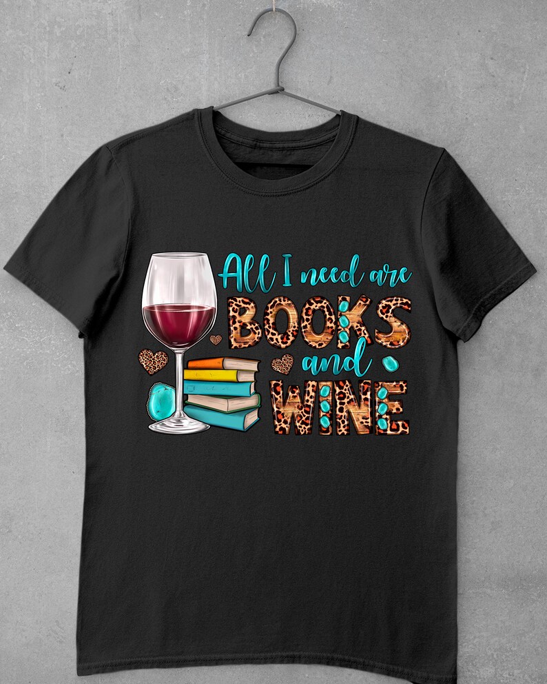May include: Black t-shirt with a graphic design of a glass of red wine and a stack of books. The text "All I need are BOOKS and WINE" is written in turquoise letters on a leopard print background.