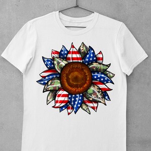 May include: White t-shirt with a red, white, and blue sunflower design. The sunflower petals are patterned with the American flag and camouflage.