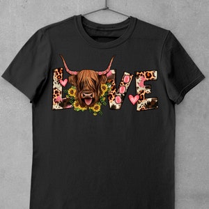 May include: Black t-shirt featuring a graphic of a Highland cow with a pink heart and the word "LOVE" in a leopard print pattern.