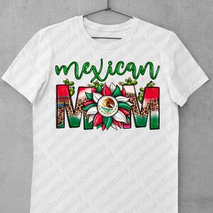 May include: White t-shirt featuring the words "Mexican Mom" in green script. The word "MOM" is designed with a floral pattern, leopard print, and the Mexican flag's emblem. Cacti accents are placed around the letters.