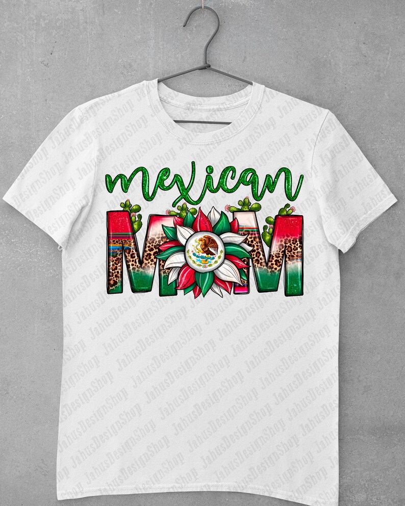 May include: White t-shirt featuring the words "Mexican Mom" in green script. The word "MOM" is designed with a floral pattern, leopard print, and the Mexican flag's emblem. Cacti accents are placed around the letters.