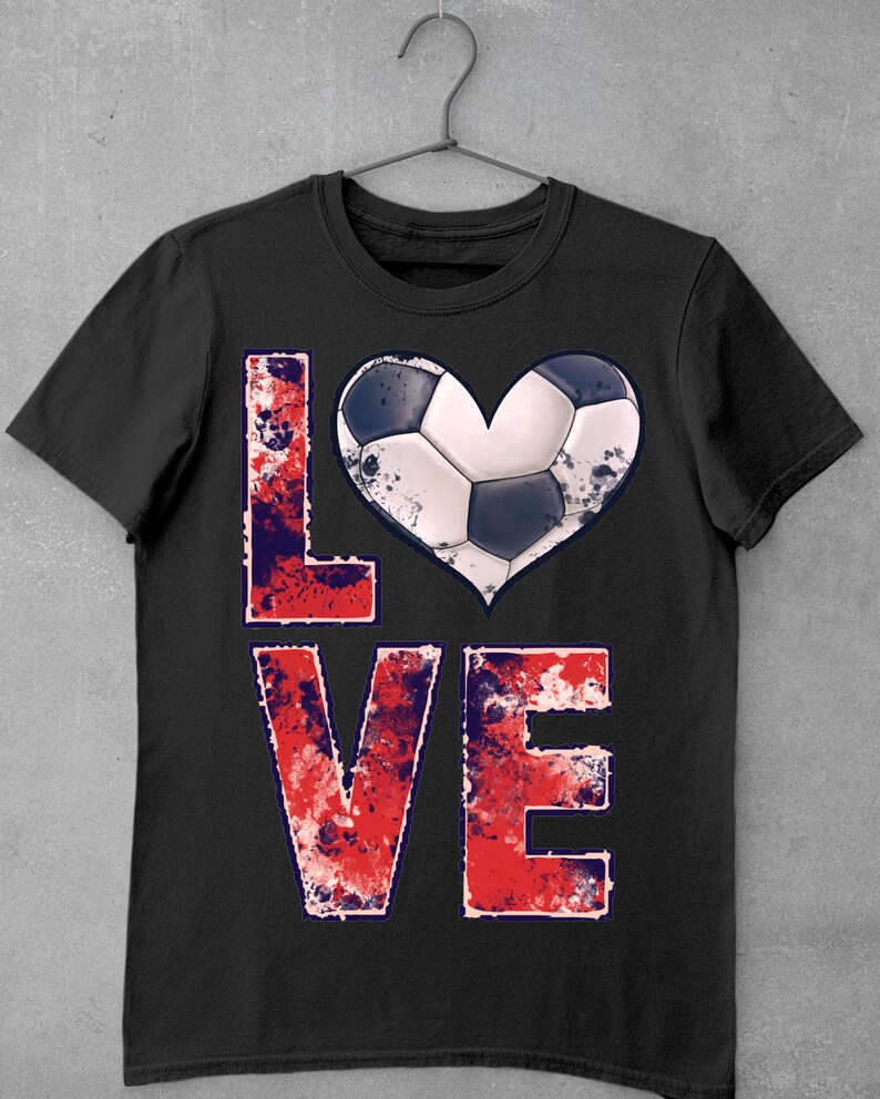 Puede incluir: Camiseta negra con un gr&aacute;fico desgastado en rojo, blanco y azul de la palabra "LOVE" con un bal&oacute;n de f&uacute;tbol en forma de coraz&oacute;n.