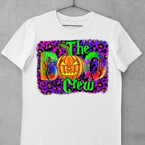 May include: White t-shirt with a colourful graphic design featuring a pumpkin, the words "The Boo Crew", and a leopard print background.