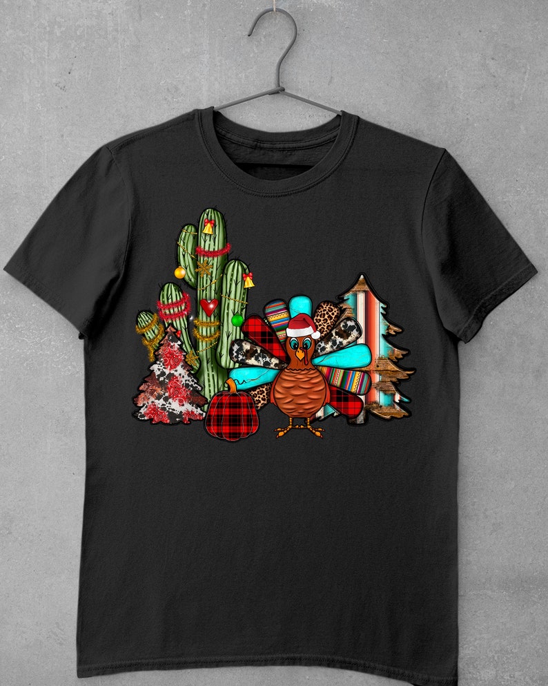 May include: A black t-shirt featuring a festive design with a turkey wearing a Santa hat, surrounded by cacti, a Christmas tree, and a plaid pumpkin.