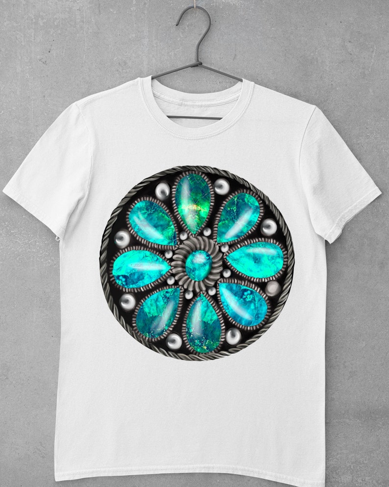 Op de afbeelding: Wit T-shirt met een cirkelvormig ontwerp in turquoise en zilver, dat lijkt op een bloem met meerdere turquoise edelstenen.