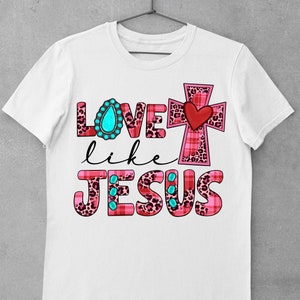 May include: White t-shirt with a pink, red, and black leopard print design that says "Love like Jesus" with a turquoise jewel and a red heart on a pink and black cross.