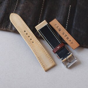 May include: A collection of watch straps in various styles. One strap is beige canvas with white stitching, another is black and beige with a brown leather accent, and a third is a leather tag with the text "CLQ. STRAP".