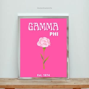Peut inclure: Une impression rose et blanche avec le texte "GAMMA PHI" et "Est. 1874" sur un fond rose vif. Un œillet rose se trouve au centre de l'impression.