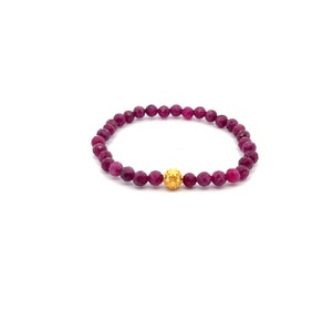 May include: A purple gemstone beaded bracelet with a gold bead accent.