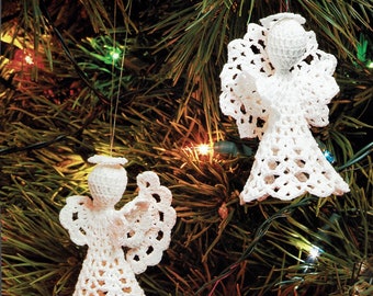 May include: Two white crocheted angel ornaments hanging on a Christmas tree with colorful lights.