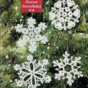 May include: Four white crocheted snowflakes hanging on a green Christmas tree. The tag reads "Forever Snowflakes".