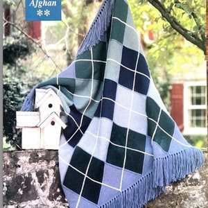 May include: A blue and green argyle patterned knitted throw blanket with fringe. The blanket is draped over a wooden surface and has the text "11 Argyle Afghan" on a blue square.