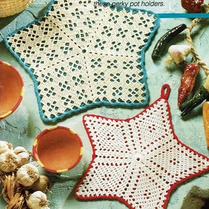 Puede incluir: Dos agarraderas de olla de ganchillo en forma de estrella. Una es blanca con un borde azul y la otra es blanca con un borde rojo. El texto "Jan/Feb 1991 Hooked on Crochet 33" es visible en la esquina inferior derecha de la imagen.