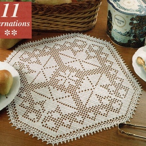 May include: A white crocheted doily with a delicate floral pattern. The doily is laid on a wooden table with a plate of fruit, a tea tin, and a cup and saucer.