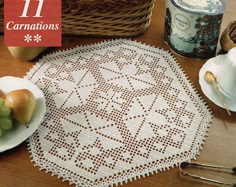 Puede incluir: Un mantel de encaje blanco con un delicado patrón floral. El mantel está colocado sobre una mesa de madera con un plato de fruta, una lata de té y una taza y un platillo.