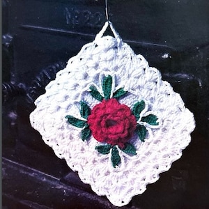 May include: White crocheted pot holder with a red rose and green leaves in the center.