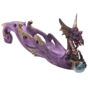 Könnte beinhalten: Lilafarbener Drachen-Räucherofen mit goldenen Akzenten. Der Drache ist um eine türkisfarbene Kugel gewickelt. Der Räucherofen ist für Räucherstäbchen konzipiert.
