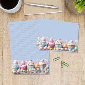 May include: Light blue stationery with pink lined paper and a decorative border featuring cupcakes and Easter eggs. The image includes a cup of coffee, a pen, and green paper clips on a wooden surface.