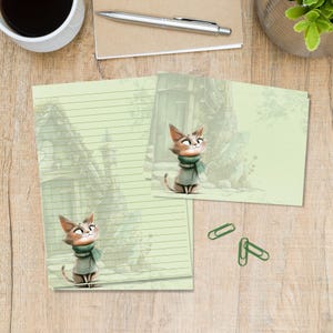 Op de afbeelding: Een lichtgroene briefpapierset met een cartoonkat die een groene sjaal en jas draagt. Het ontwerp bevat een gelinieerd vel en een bijpassende kaart, beide versierd met een zachte illustratie van de kat voor een stenen gebouw.
