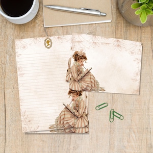 May include: A vintage stationery set with lined and blank paper, featuring an illustration of a woman writing. The paper has a floral border and a cameo design. Includes two green paper clips. A pen and a cup of coffee are also visible.