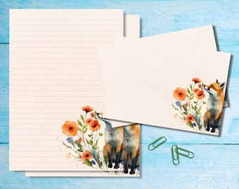 May include: A set of two blank stationery cards with a watercolor illustration of two foxes sniffing flowers. The illustration features orange and red flowers, green leaves, and a light blue background.